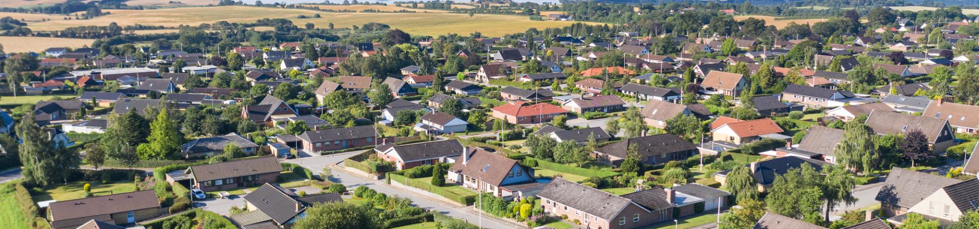 Parcelhuse taget oppefra med vand i horisonten.